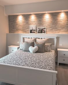 a white bed with pillows and two pictures on the wall above it's headboard