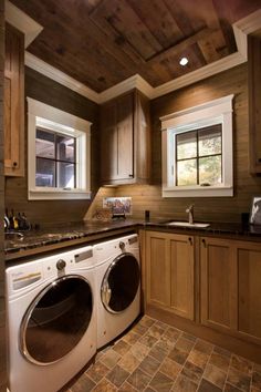 a washer and dryer in a kitchen with wood paneling on the walls