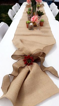 the table is set up with flowers and burlocked linens on it