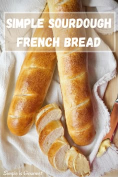 two loaves of bread sitting on top of a white towel next to a knife