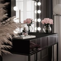 a table with flowers and candles on it in front of a mirror that is lit up