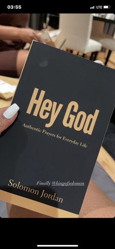 a person holding up a book with the title hey god written in gold on it