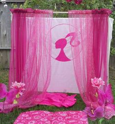 a pink and white canopy sitting on top of a lush green field next to flowers