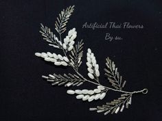 a brooch with some white flowers and leaves on it's back side that says artificial thai flowers by su