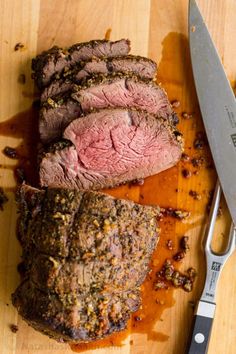 sliced meat on cutting board with knife and sauce