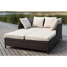 an outdoor sectional sofa with cushions on a wooden deck next to a body of water