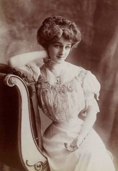 an old black and white photo of a woman sitting on a chair