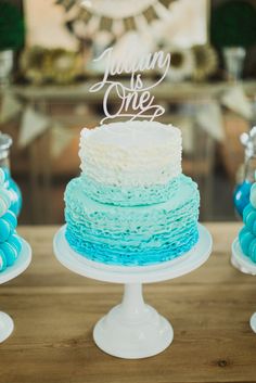 a blue and white cake sitting on top of a table next to other desserts