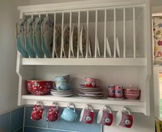 a shelf filled with dishes and cups next to a window