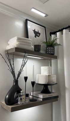 a shelf with candles, towels and other items on it in a room that has white walls