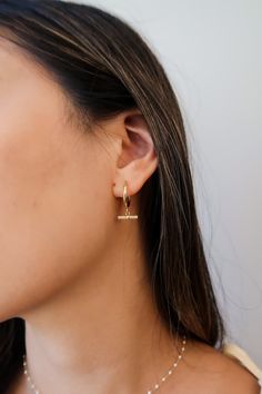 Expertly crafted in Italy, these 14mm hoop earrings are a timeless addition to any jewelry collection. These dainty and modern earrings feature a small T-bar dangling from a delicate hoop, accented with a row of small stones for a touch of sparkle. Elevate your style with our Gold and Stones Toggle Earrings. Make a statement and add this unique piece to your collection. Details: Metals: 14kt 1-Micron Gold-Plated on Sterling Silver Base Stones: AAAAA-Grade Cubic Zirconia Anti-Tarnish Coating Elegant 14k Gold Charm Earrings, Formal Gold-tone Tarnish Resistant Earrings, Chic Gold-tone Drop Earrings, Formal Multi-stone 14k Gold Earrings, Elegant Multi-stone 14k Gold Earrings, Formal Earrings, Pearl Pendant Necklace, Cartilage Earrings, Pearl Stud Earrings