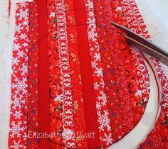 a pair of scissors and some red strips on a white table with snowflakes