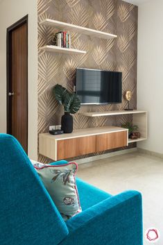 a blue chair sitting in front of a tv on a wooden entertainment center next to a wall mounted television