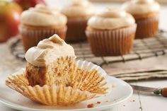 cupcakes with frosting sitting on top of a white plate next to an apple