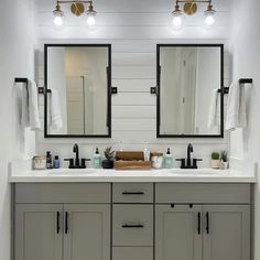 a bathroom with two sinks, mirrors and lights on the wall above them is shown