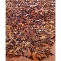 a pile of brown leaves sitting on top of a wooden floor next to a rug