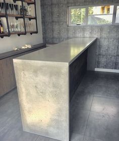 a counter top sitting in the middle of a room next to a wall with bottles on it