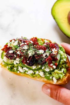 someone is holding up a piece of bread with vegetables on it