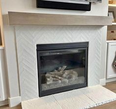 a white fireplace with a television above it