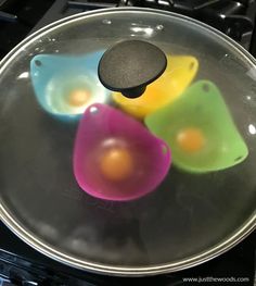 four colorful bowls sitting on top of an oven burner with one egg in the middle