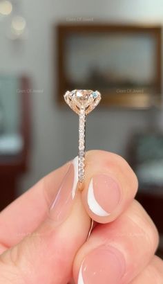 a woman's hand holding an engagement ring with a diamond on the top and bottom