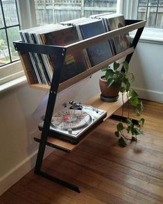 a record player is sitting on a shelf in front of a window with books and plants