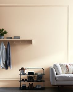 a white couch sitting next to a shelf filled with shoes and blankets on top of it