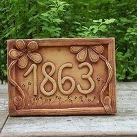 a plaque with the number 1383 on it sitting in front of some bushes and trees