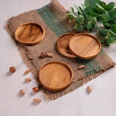 three wooden bowls sitting on top of a table next to green leaves and nuts in front of them