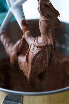 a metal mixing bowl filled with chocolate frosting