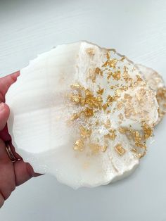 a person is holding a piece of white and gold rock with some gold flakes on it