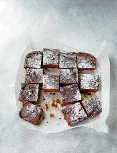 some brownies are on a white plate with powdered sugar