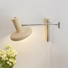 a lamp that is on the side of a wall next to a vase with flowers