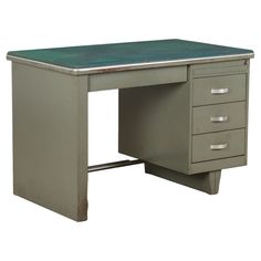 an old metal desk with three drawers and a green top is shown against a white background