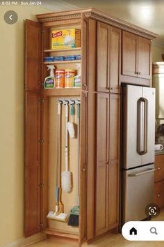 a kitchen with wooden cabinets and cleaning supplies in the cupboards next to the refrigerator