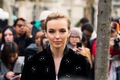 a woman is standing in front of a group of people and taking pictures with her cell phone