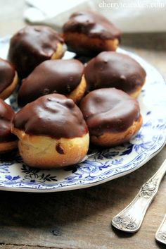 chocolate covered donuts on a blue and white plate with silverware next to it