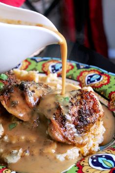 someone is pouring gravy over some food on a plate