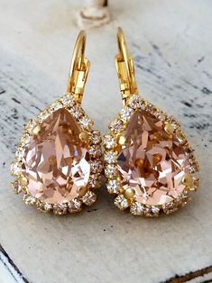 "Pink blush crystal earrings, Tear drop earrings, Bridal earrings, Bridesmaids gifts, Dangle earrings, Gold or silver, Swarovski earrings, Vintage earrings Elegant and refined. These earrings have a wonderful soft blush pink center stone surrounded by clear crystal stones - so much sparkle. They would be great as bridal earrings or for any other day. Perfect gift for bridesmaids or other occasions. They are made of 14k gold plated brass posts and Swarovski crystals, all set in prong setting. Mad Blush Pink Earrings, Bridal Dangle Earrings, Pink Drop Earrings, Rose Gold Drop Earrings, Morganite Earrings, Blush Earrings, Peach Earrings, Wedding Earring, Crystal Teardrop Earrings