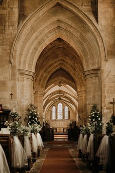 a church filled with lots of pews covered in white tulle and flower arrangements