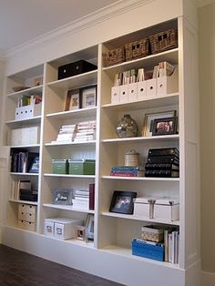 a white book shelf filled with lots of books on top of a hard wood floor