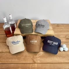 four hats sitting on top of a wooden table next to two bottles of beer and golf balls