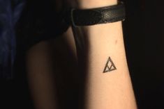 a woman's arm with a small triangle tattoo on her left wrist, and a black band around the wrist