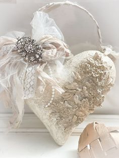 a white heart shaped box sitting on top of a table next to an ornament