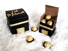 a box filled with chocolates sitting on top of a white blanket next to some gold foil