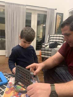 a man sitting next to a boy who is playing with a board game