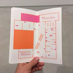 a hand holding an open book with orange and pink designs on it's pages