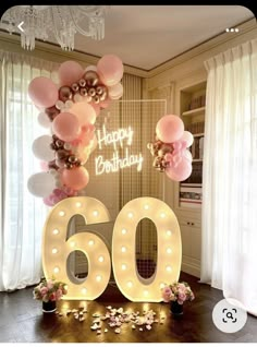 a birthday party with balloons and lights in the shape of the number sixty, surrounded by confetti