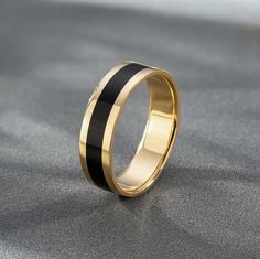 a gold ring with black stripes on the outside and inside, sitting on a gray surface