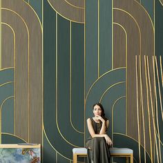 a woman is sitting on a chair in front of a wall with art deco designs